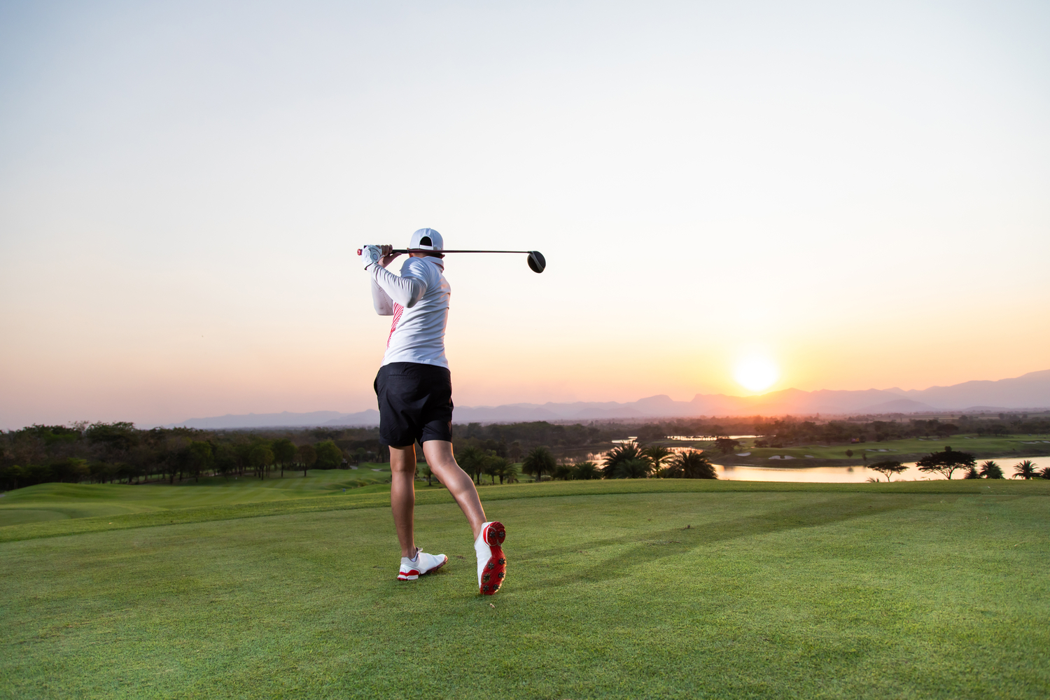 Golfer golfing at sunrise