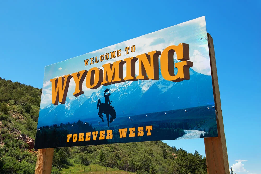 Welcome to Wyoming Forever West sign with the Teton Range and a bucking horse rider